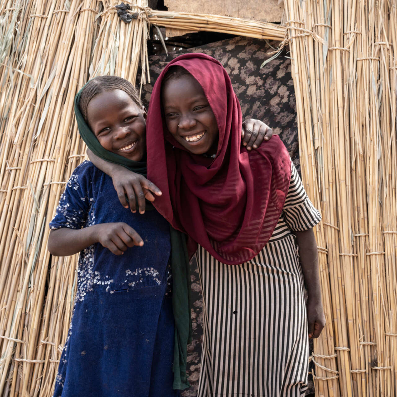 Två tjejer ler och håller om varandra.